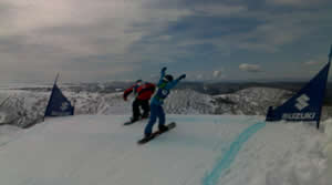 Snowboarders going over roller at Mt Hotham